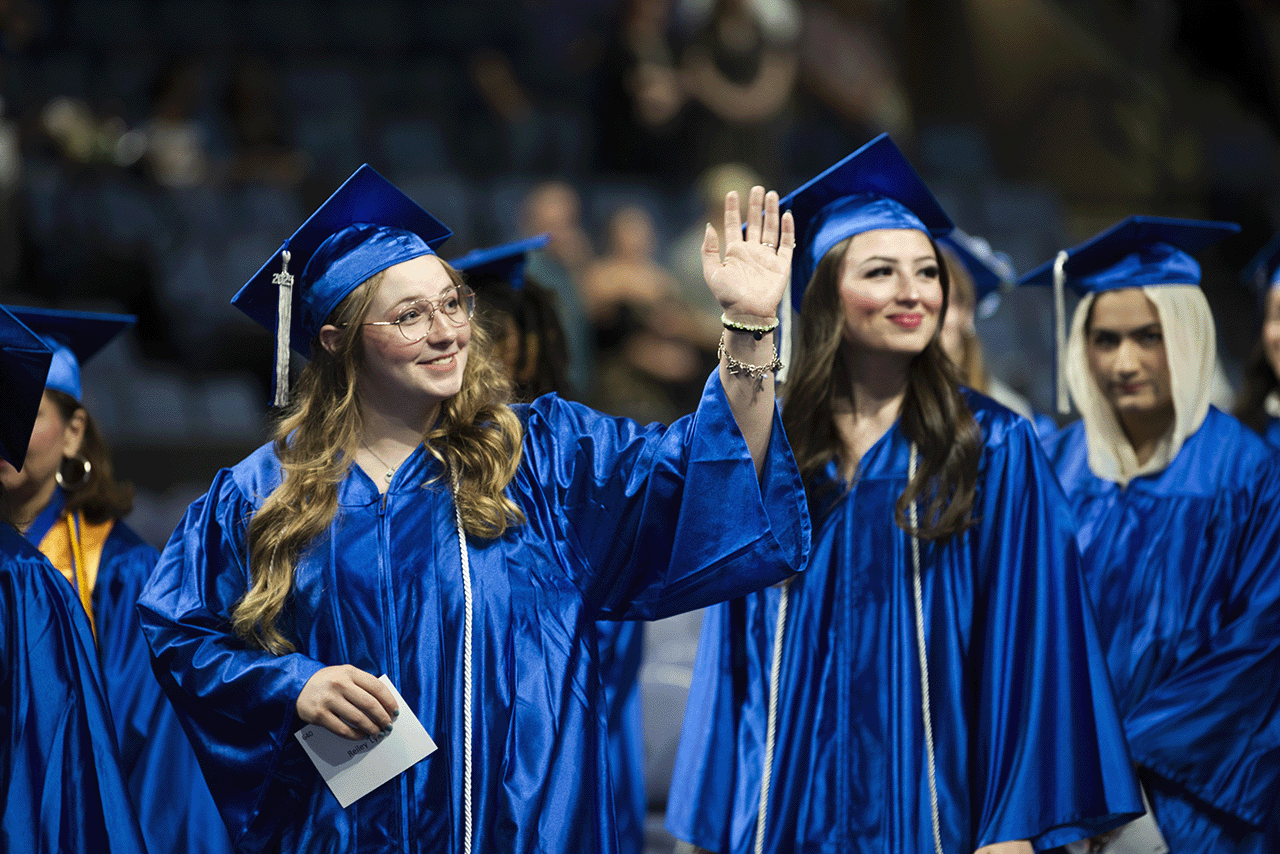 Students in a line 在 gradu在ion holding their name cards