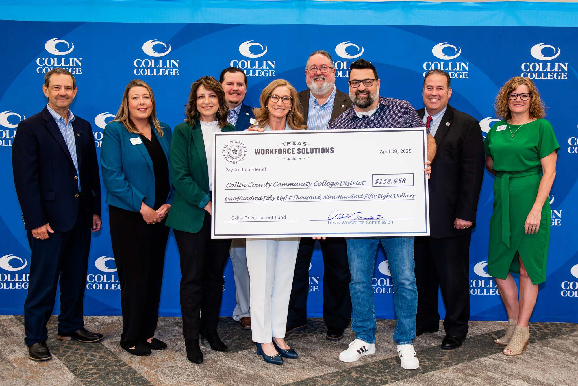 Business owners/workers and Collin College officials pose with an oversized check for $158,958 - one of four dispersed at the check signing event.