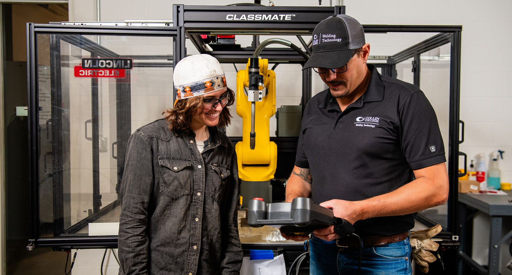 A member of the welding factory discusses automated systems with a student.