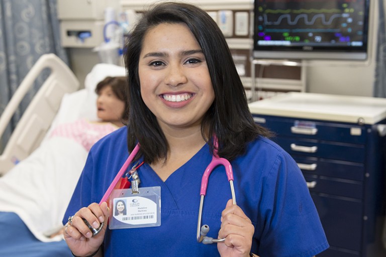 Madeline Lee Martinez, Collin College nursing student, poses with a stethoscope around her neck in a hospital simulation room.