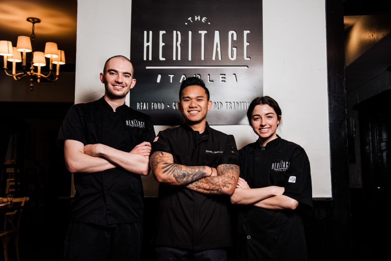 Collin College Culinary Arts alumni Jack Jasek, Leon Van, and Chelsea Cicio posing inside The Heritage Table restaurant.
