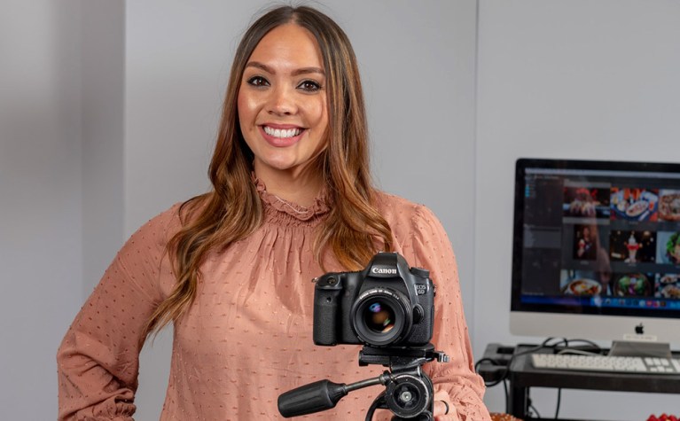 Collin College Photography student, Samantha Reynolds, smiles while posing with a DSLR camera.